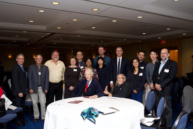 Speakers and organizers of the 2017 Earl W. Davie Symposium. Seated at the table are Dr. Earl Davie (left) and Dr. Eddy Fischer (right); the keynote speakers were Dr. Katherine A. High (standing 4th from left) and Dr. James H. Morrissey (standing at far right). Tribute authors Ross MacGillivray (standing 3rd from left) and Ed Conway (standing 2nd from left) are present for the photo as well.