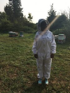Mopelola Akinlaja, who won the UBC 3MT, standing in a white bee suit on a grassy background with trees